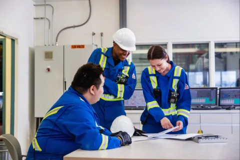 Three people gather at a desk to look at papers.